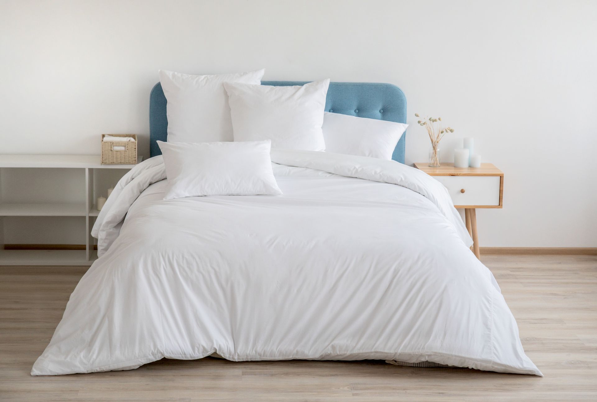 White bed with blue headboard and pillows in a minimal bedroom.