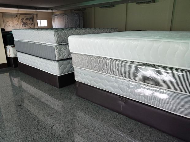 Mattresses stacked in a showroom, with white and gray patterned tops on dark bases.