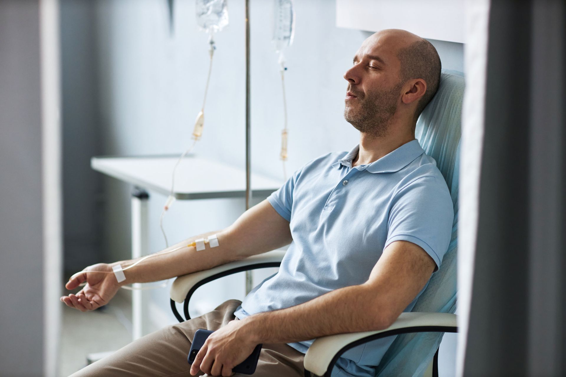 A man is sitting in a chair with an IV in his arm.