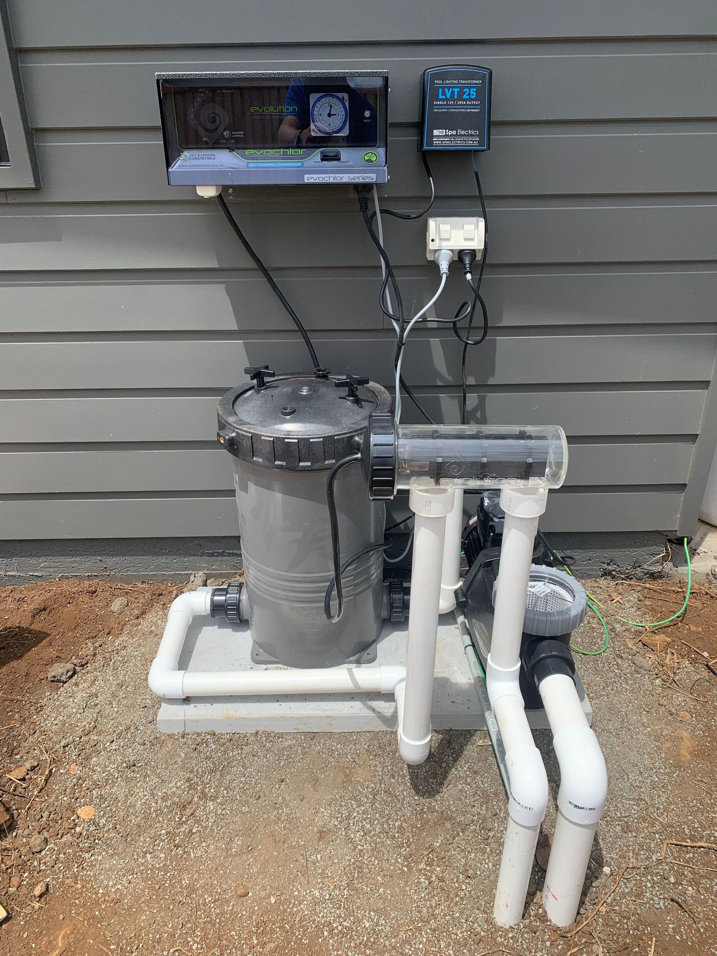 A swimming pool filter is sitting on the ground next to a house  — Pool Shop in East Ballina, NSW