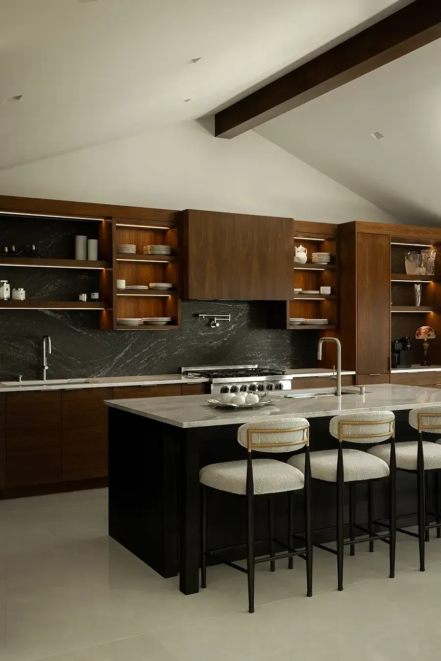 A kitchen area featuring light beige cabinets, a farmhouse sink, stainless steel stove, and marble-style countertops.