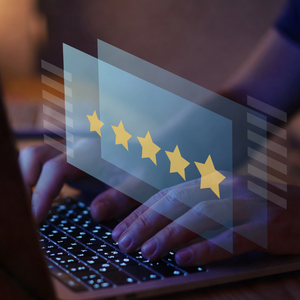 Close-up of hands typing on a laptop with a transparent 5-star rating overlay floating above the keyboard.