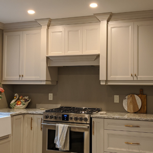 A bright kitchen features off-white cabinetry, a stainless steel gas range, and a neutral-toned backsplash.