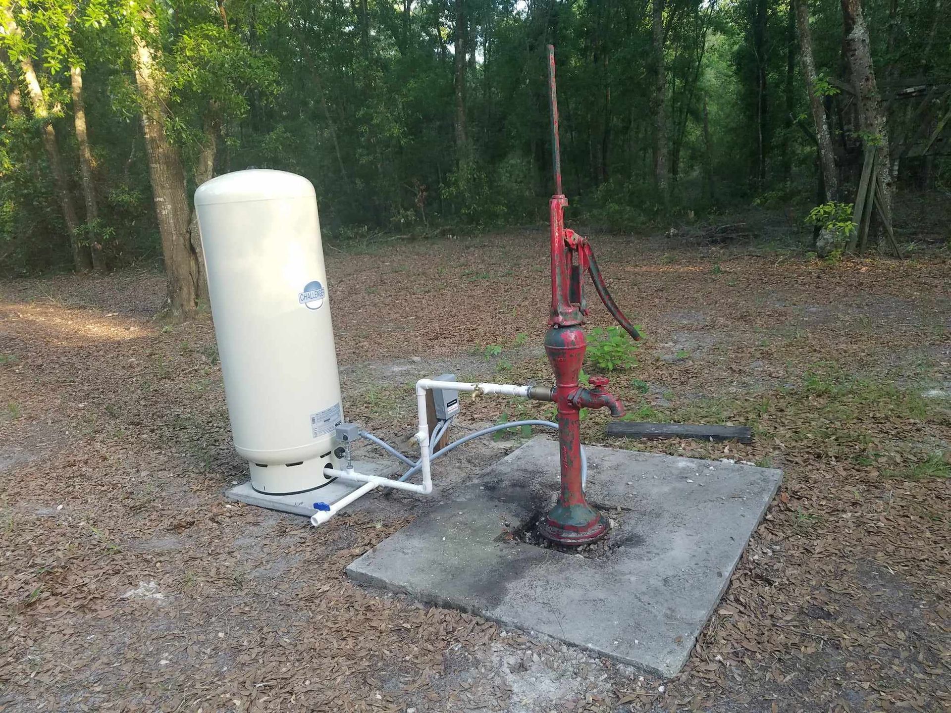 A water pump is pumping water into a stone fountain in a garden.