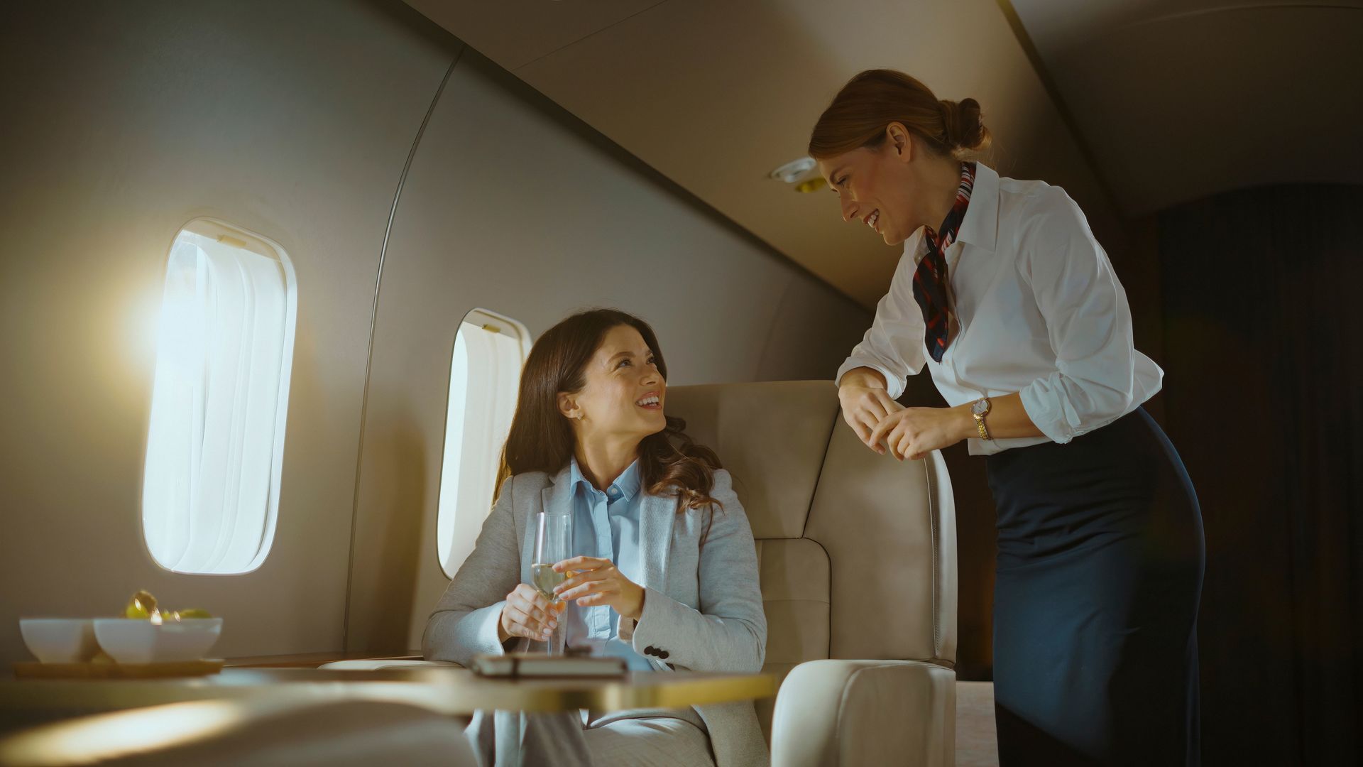 Flight attendant assisting a seated passenger in a private jet cabin