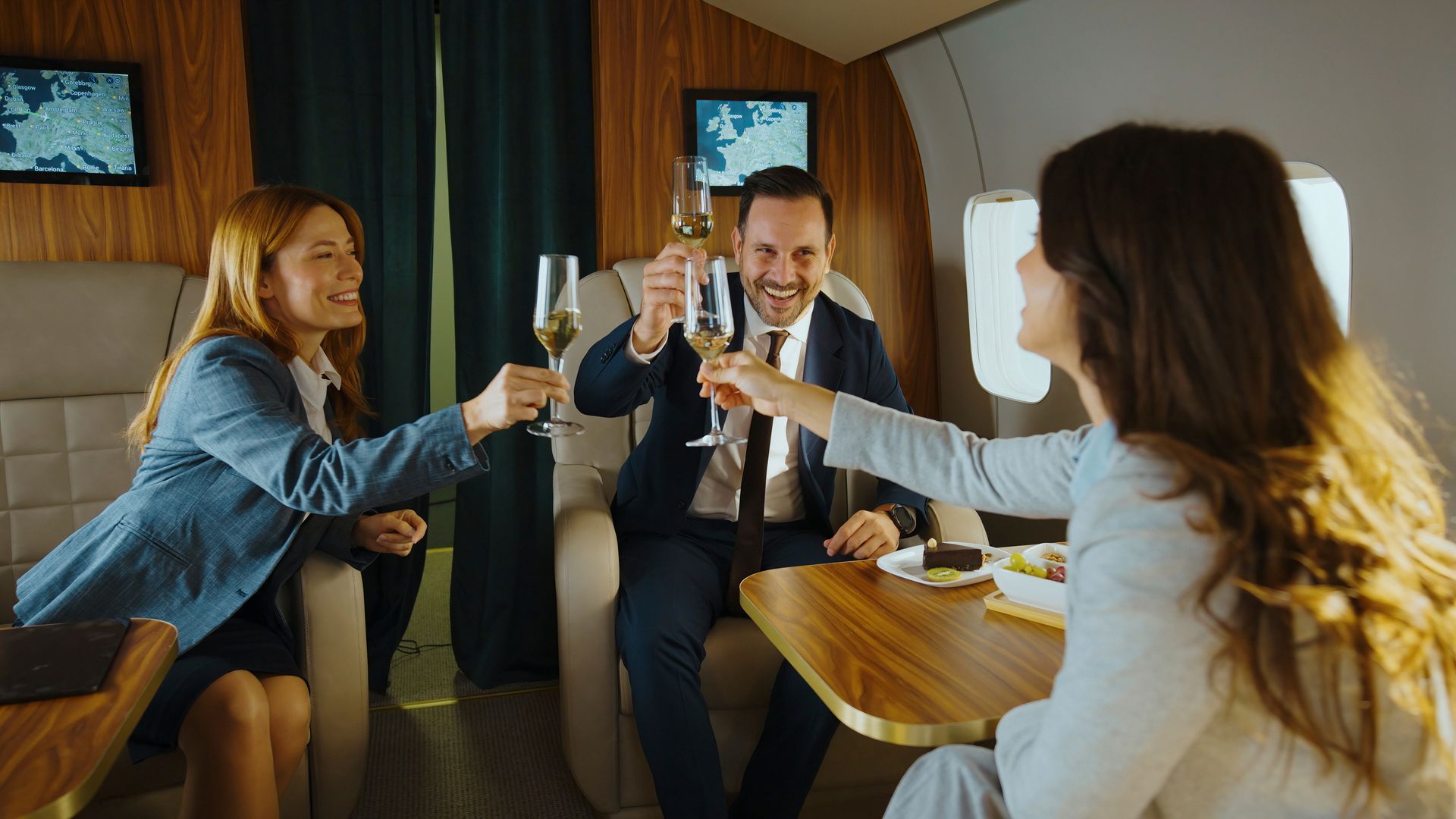 Four people clink champagne glasses together in a warmly lit train dining car.