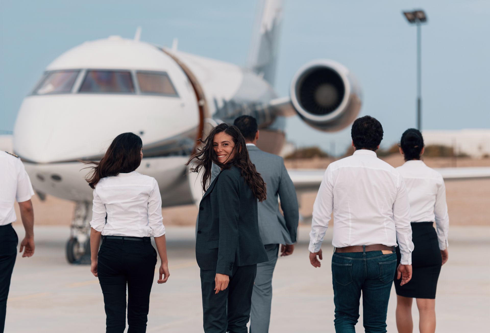 People walking toward a parked jet on an airport tarmac