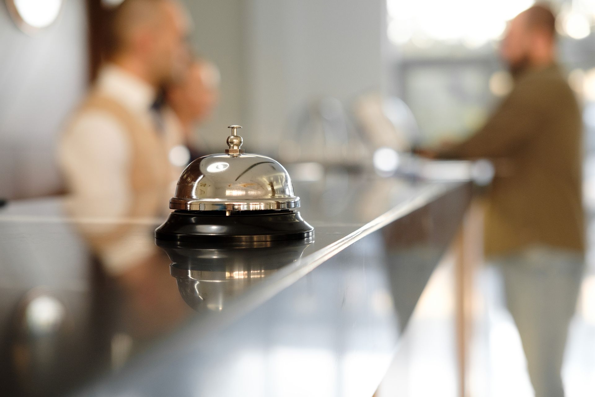 Silver service bell on a counter in a blurred hotel or restaurant lobby