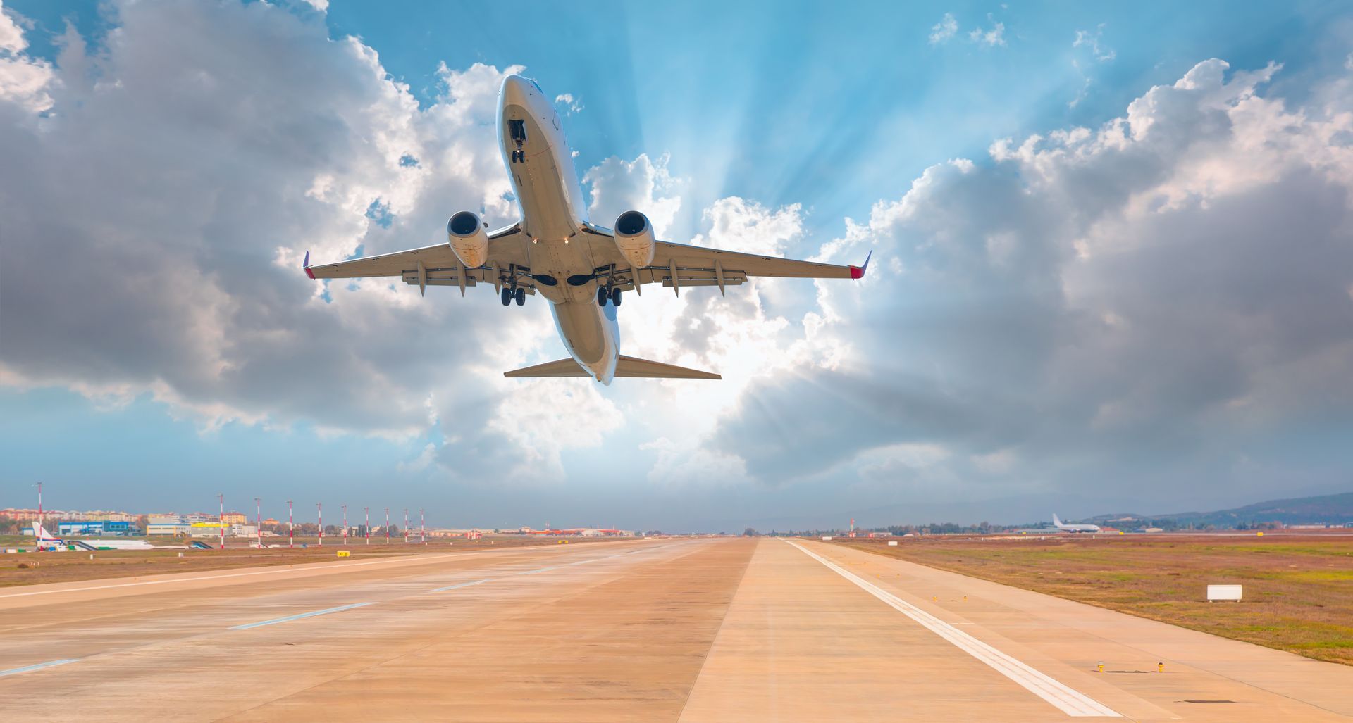 Low-flying jet over a runway under a cloudy sky, viewed from below