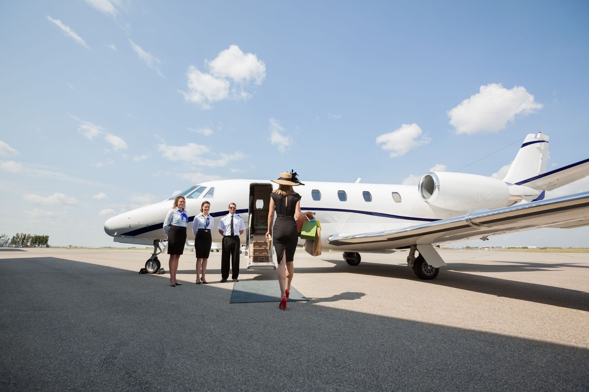 People boarding a small private jet on a sunny tarmac
