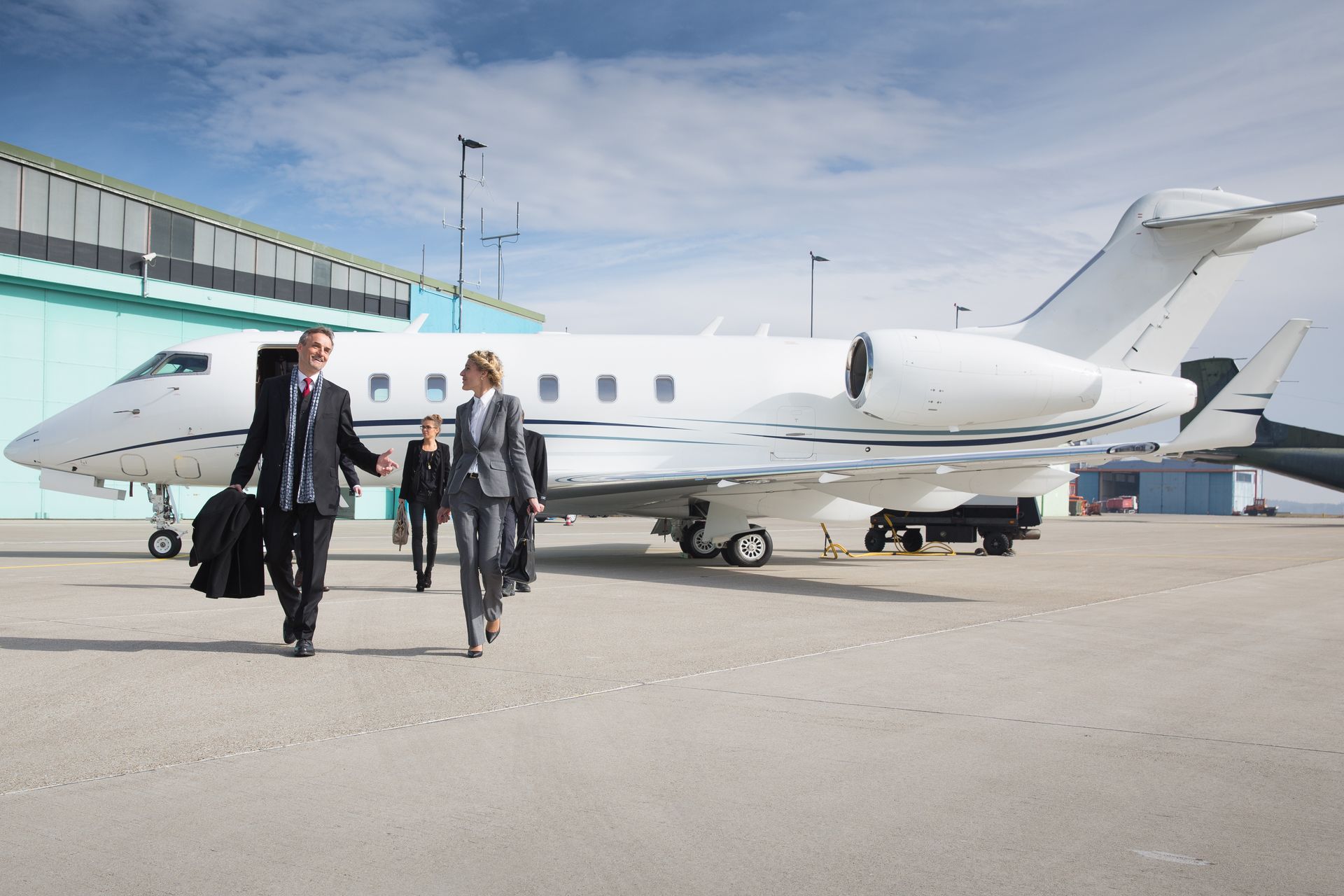 Two people walking beside a white private jet on an airport tarmac.