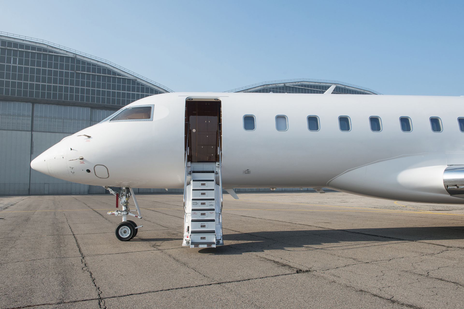 White passenger jet parked on the tarmac with open stairs at the front door
