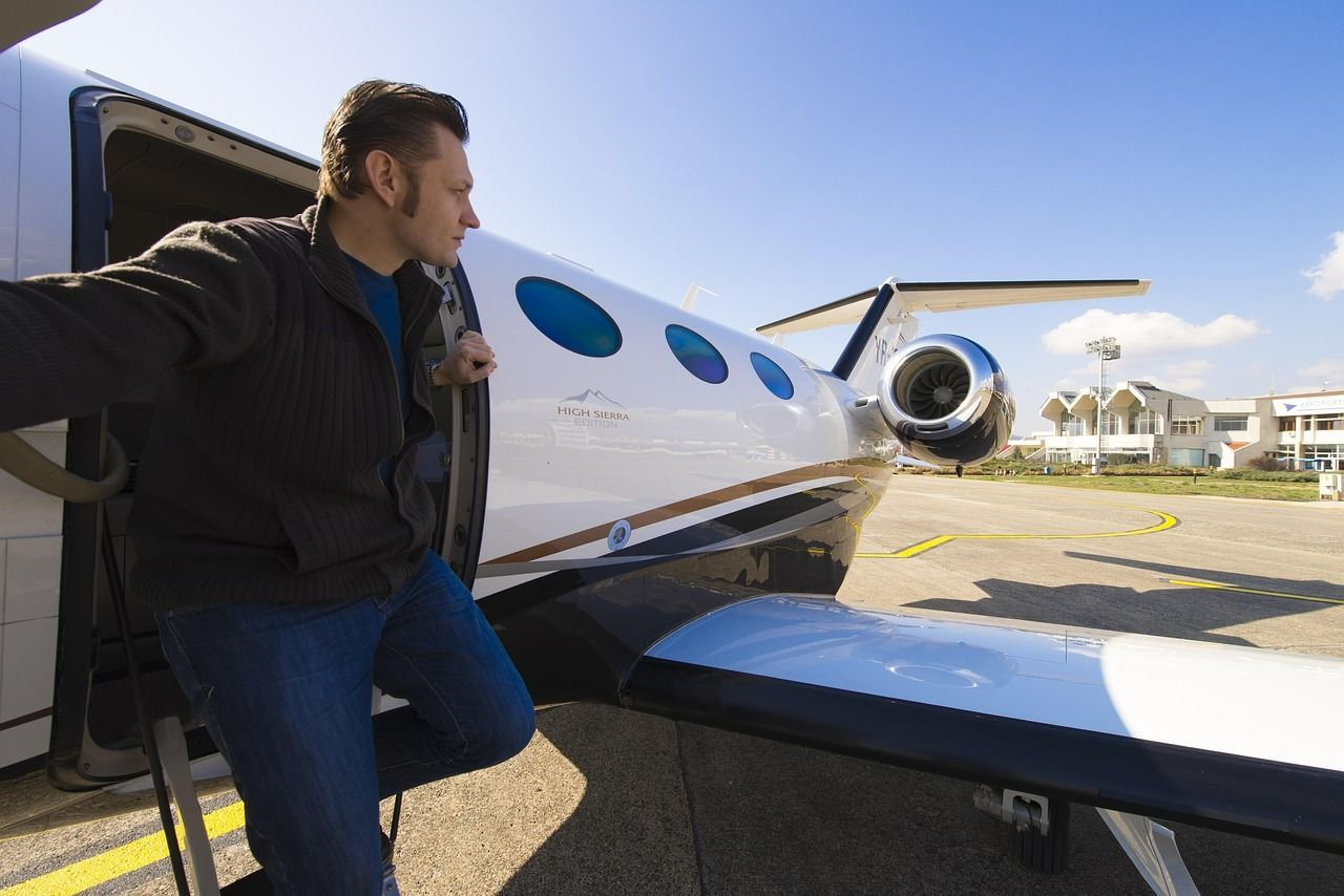 Man stepping from a private jet onto the tarmac on a sunny day