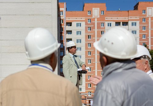 A group of men wearing hard hats are standing in front of a building.