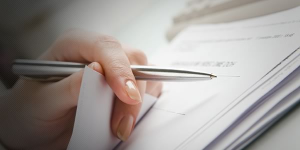 A person is writing on a piece of paper with a pen.