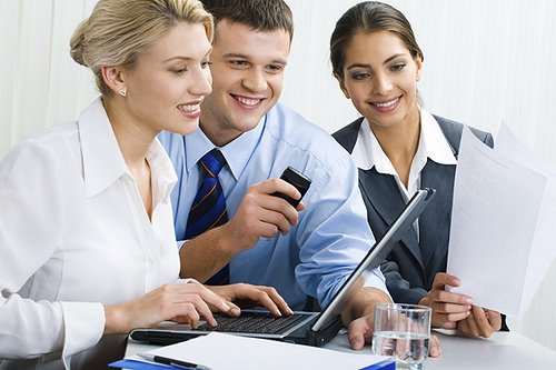 A group of people are looking at a laptop together