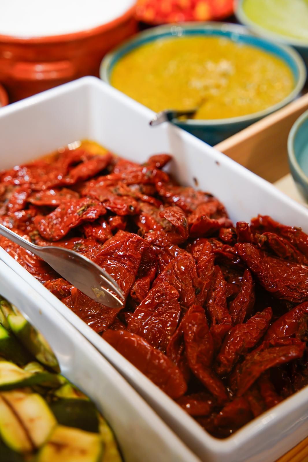 Vassoio di snack fritti in salsa rossa con cucchiaio da portata, circondato da ciotole di curry e verdure.