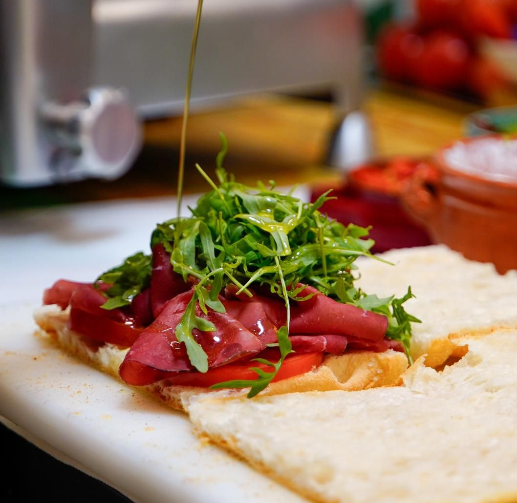 Olio d'oliva che cola su una focaccia in stile caprese con pomodori e verdure in una cucina