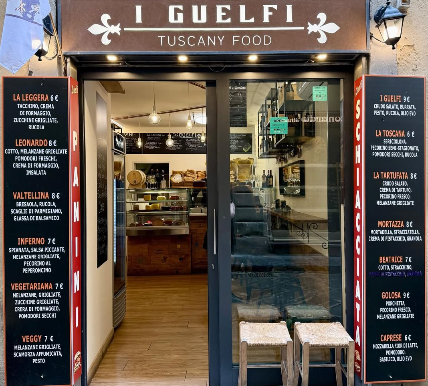 Ingresso del ristorante I Guelfi Tuscany Food con menù in lavagna e porta a vetri che si apre su un interno accogliente