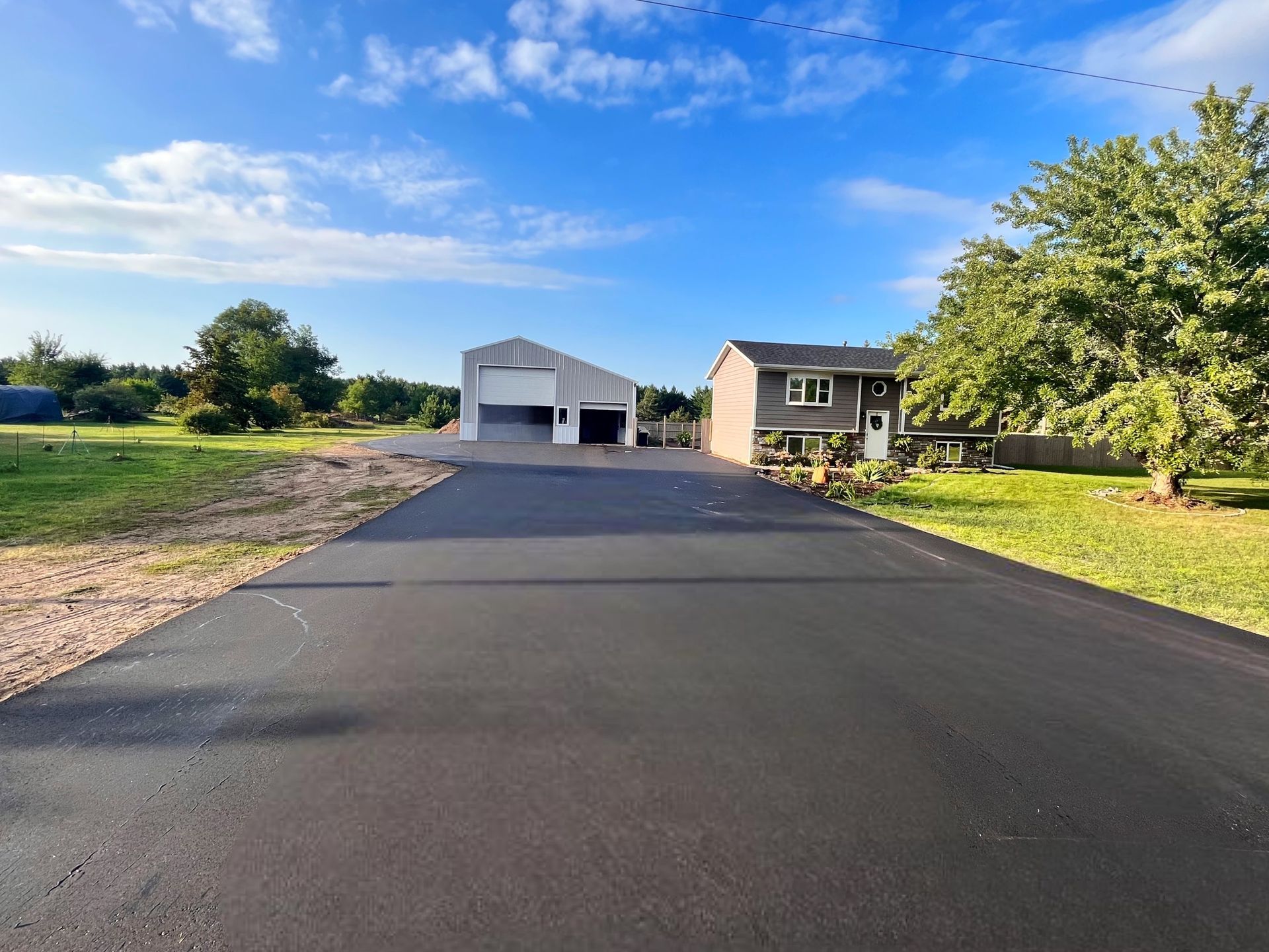 a driveway with garages and grass and trees
