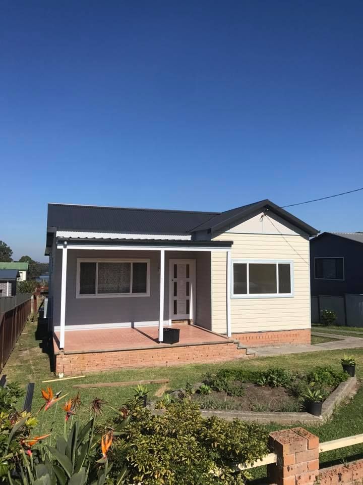 A Small House With a Porch and a Fence in Front of It — Nathan Parnell Roofing In Vincentia, NSW