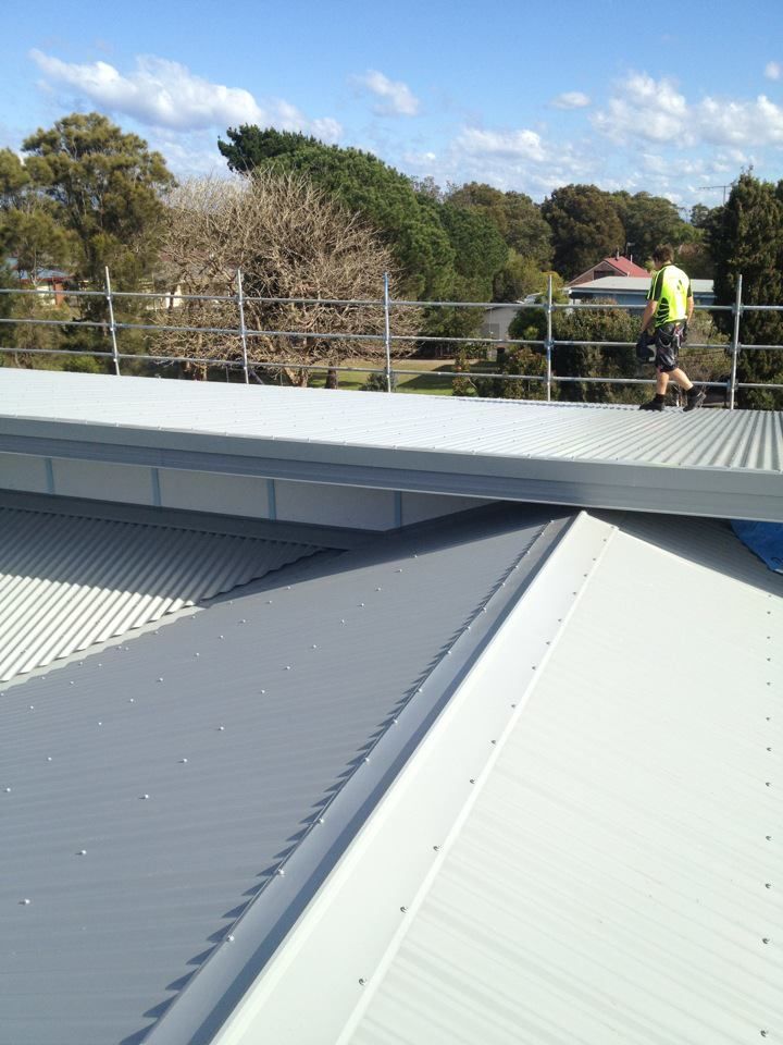 A Man is Walking on the Roof of a Building  — Nathan Parnell Roofing In Culburra, NSW
