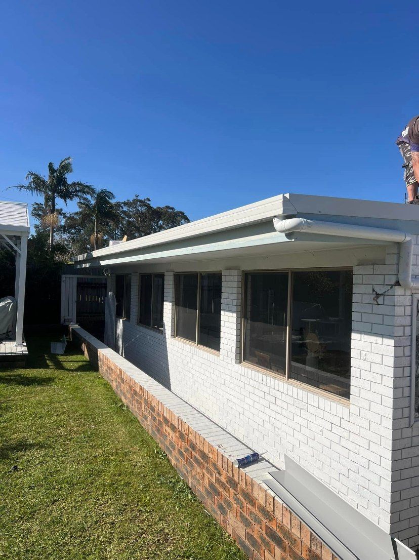 A White Brick House With a Lot of Windows — Nathan Parnell Roofing In Ulladulla, NSW