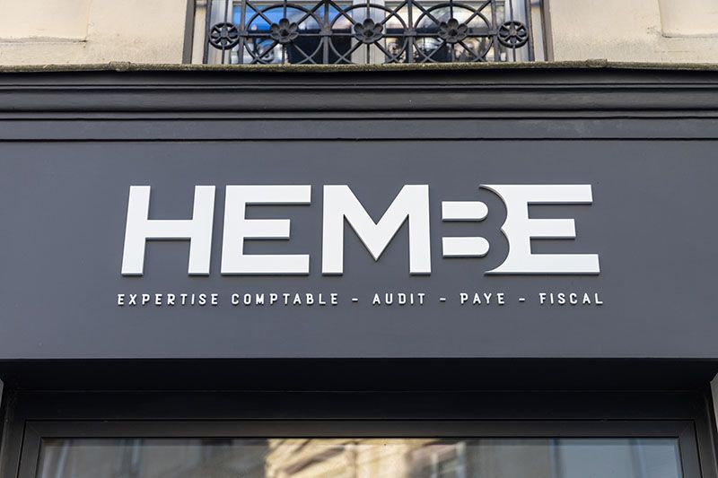 Enseigne bandeau noire à lettres blanches sur la façade d’une boutique parisienne