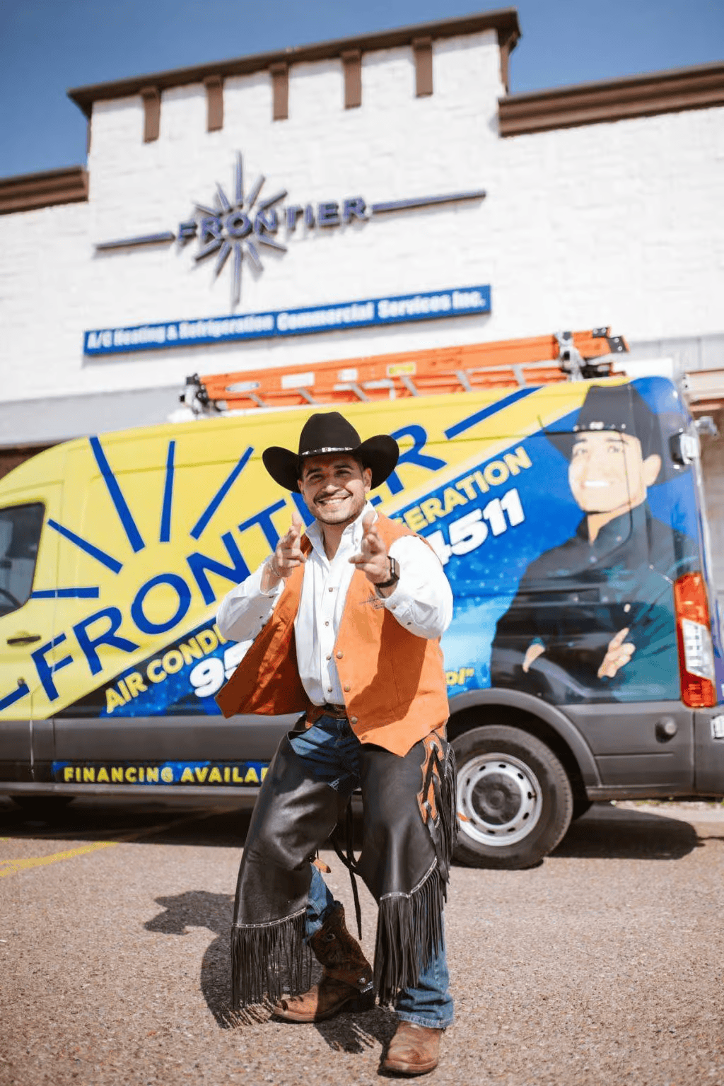 Man in cowboy attire gesturing in front of a Frontier Air Conditioning van. Building in background.
