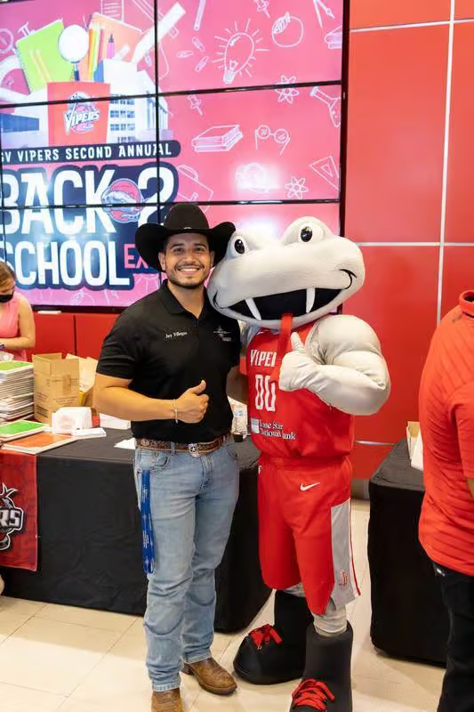 Man in cowboy hat with mascot giving thumbs up at a back-to-school event.