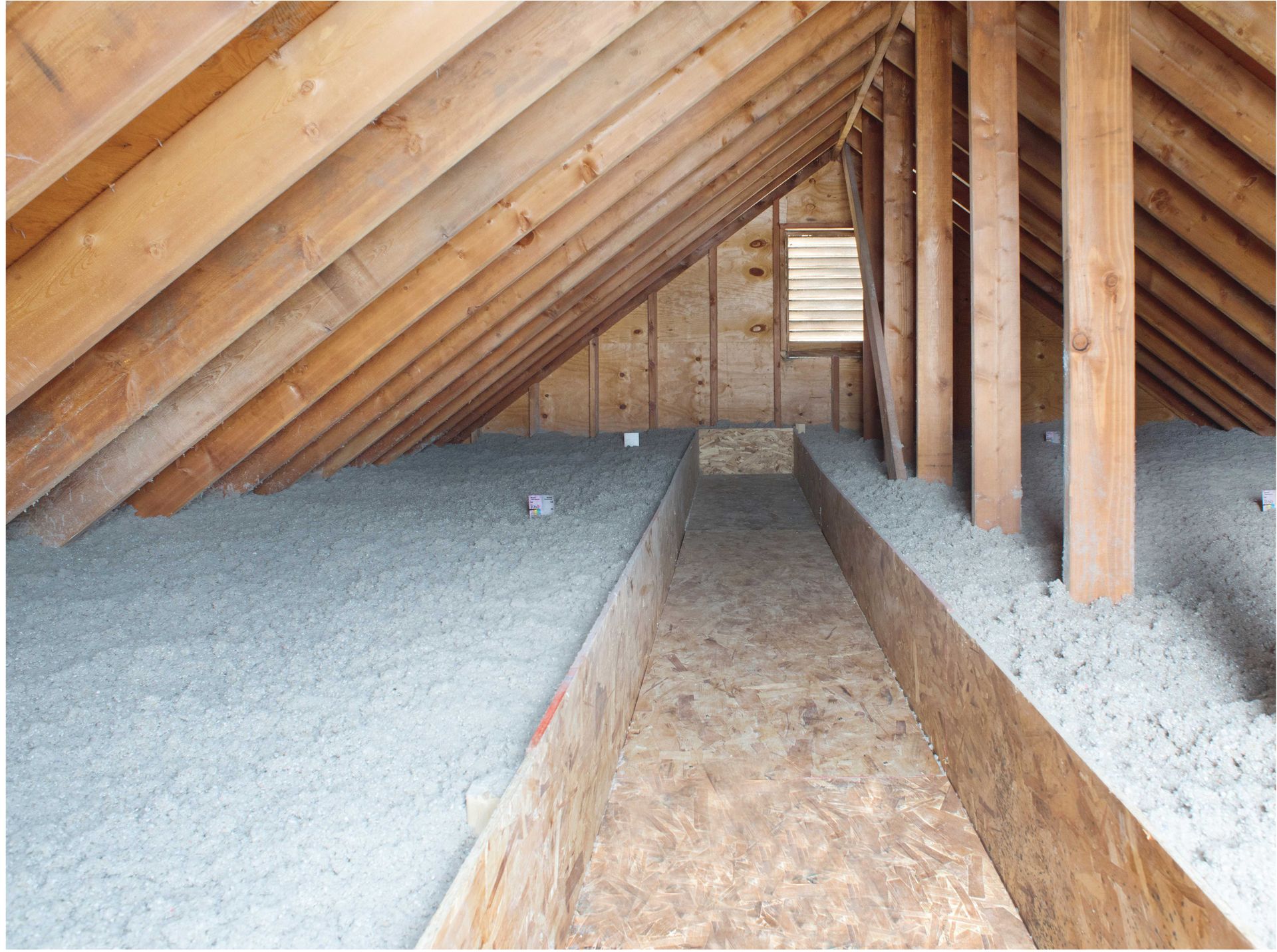 Attic with wood framing, insulation, and a central walkway.