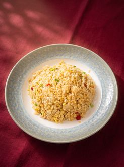 A bowl of crumbly rice or grain dish on a red cloth background.