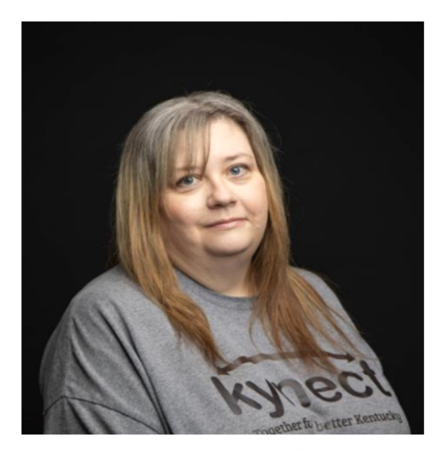 Portrait of a woman in a gray shirt against a black background