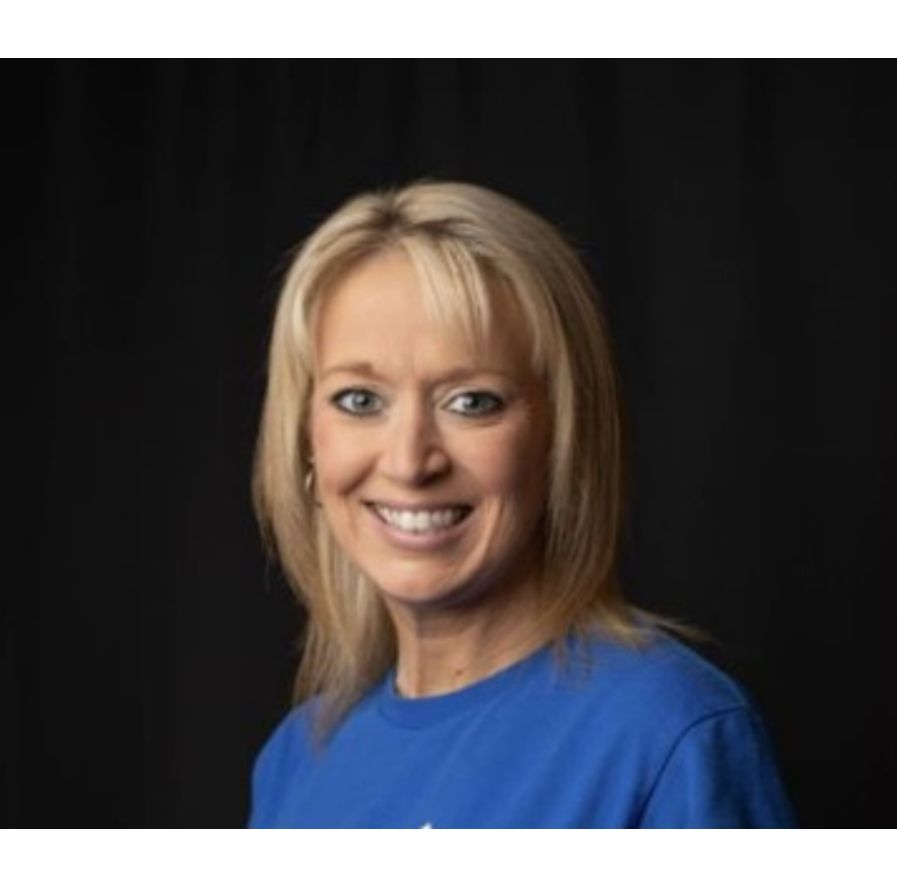 Smiling blonde woman in a blue shirt against a dark background