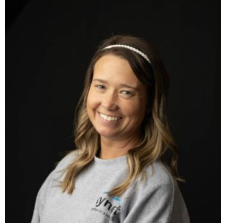 Smiling woman in a gray sweatshirt and headband against a black background