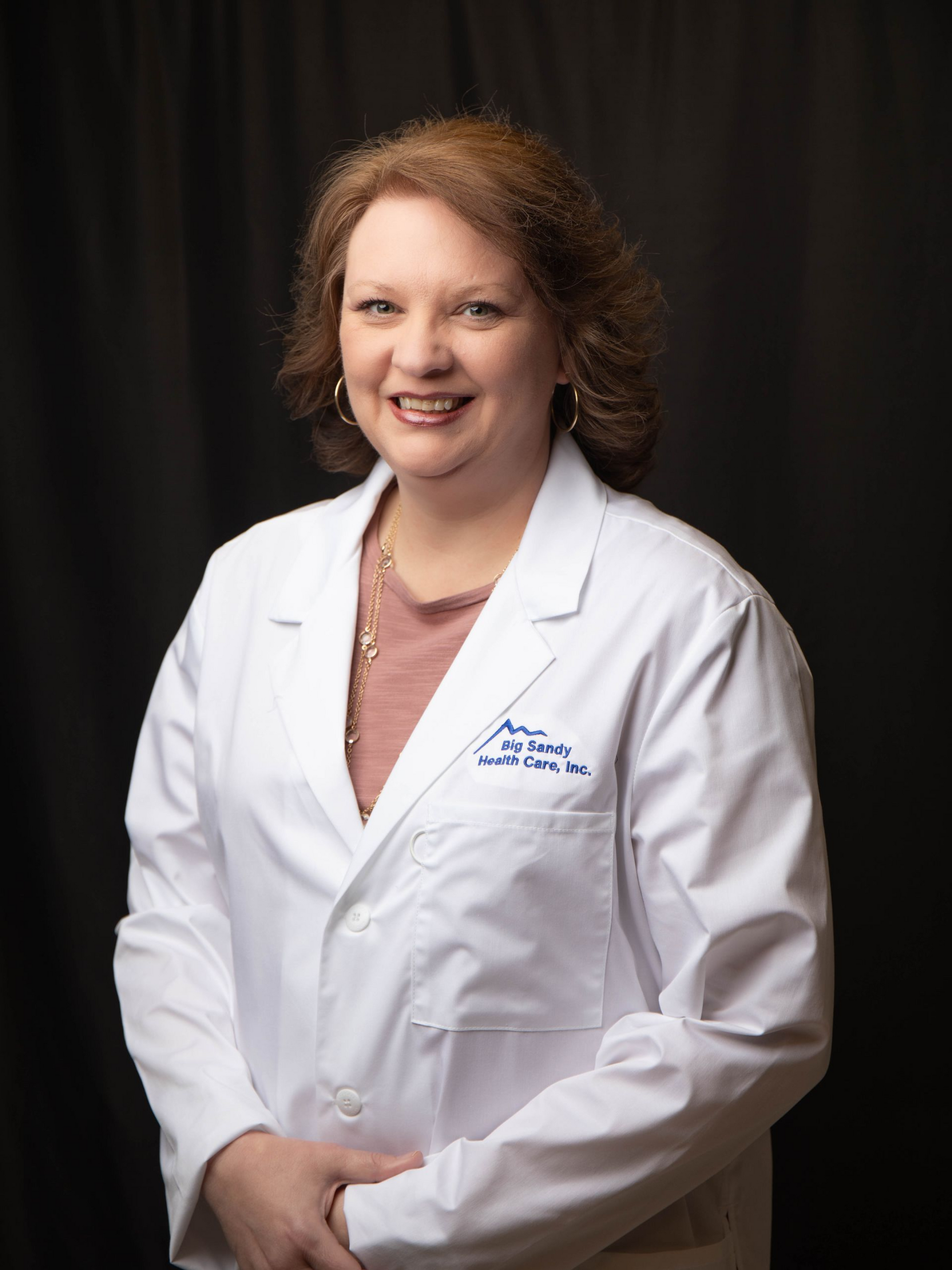 Smiling doctor in a white coat with a pink stethoscope against a black background
