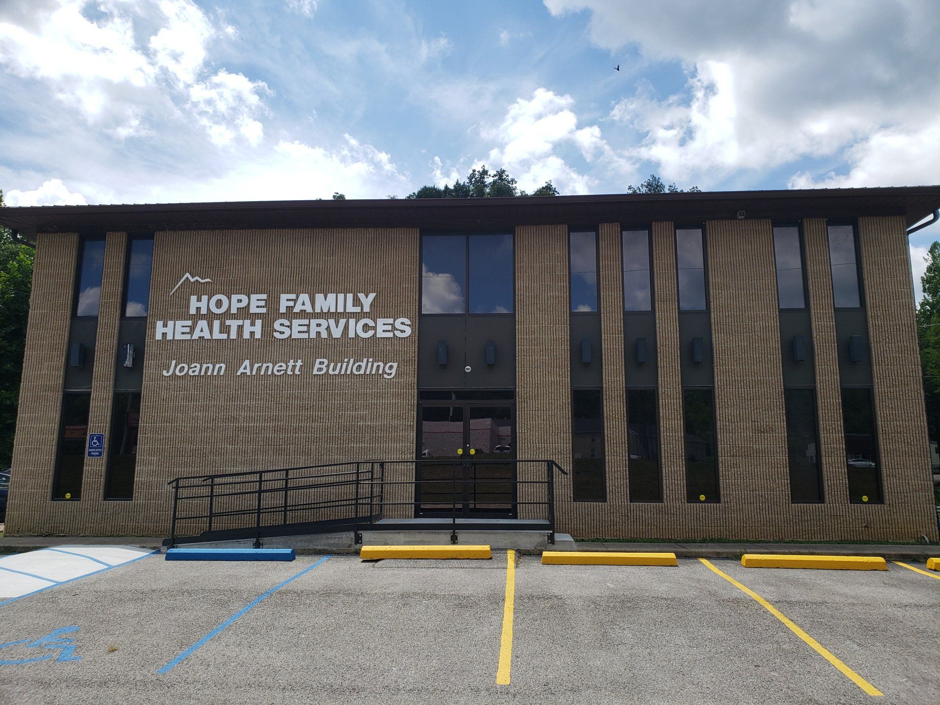 Hope Family Health Services building with brick facade, black railings, and empty parking spaces