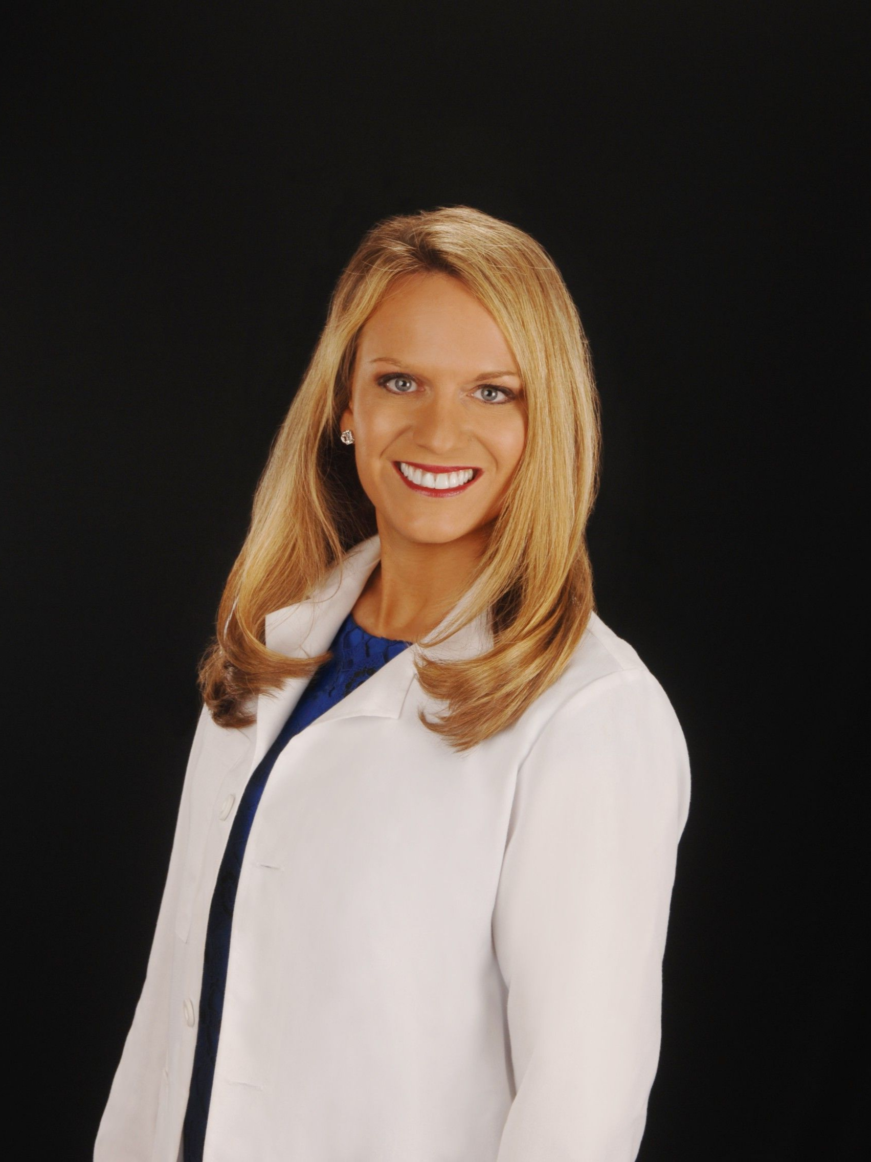 Smiling doctor in a white lab coat against a black background