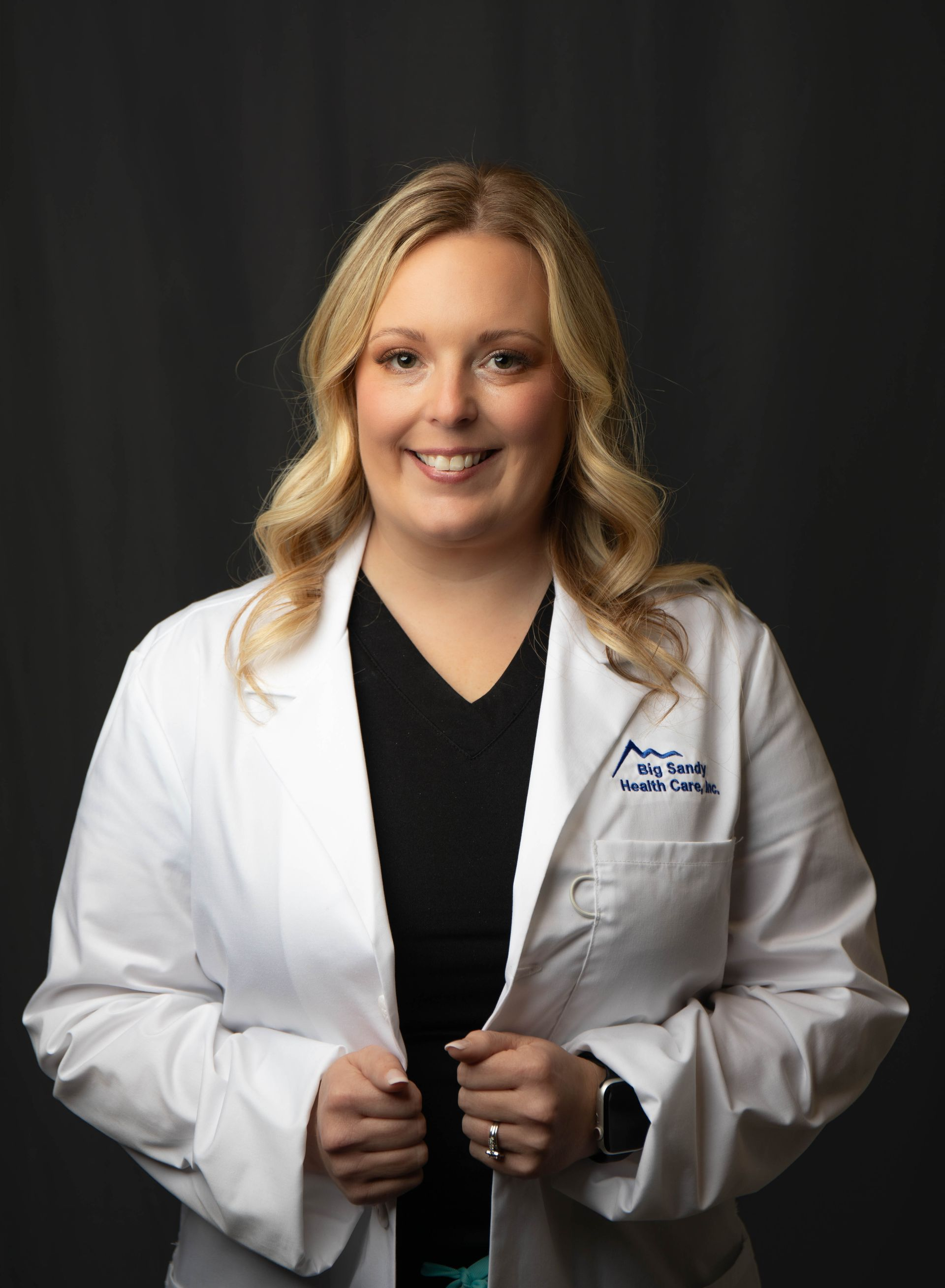 Smiling doctor in white coat with stethoscope against a dark background