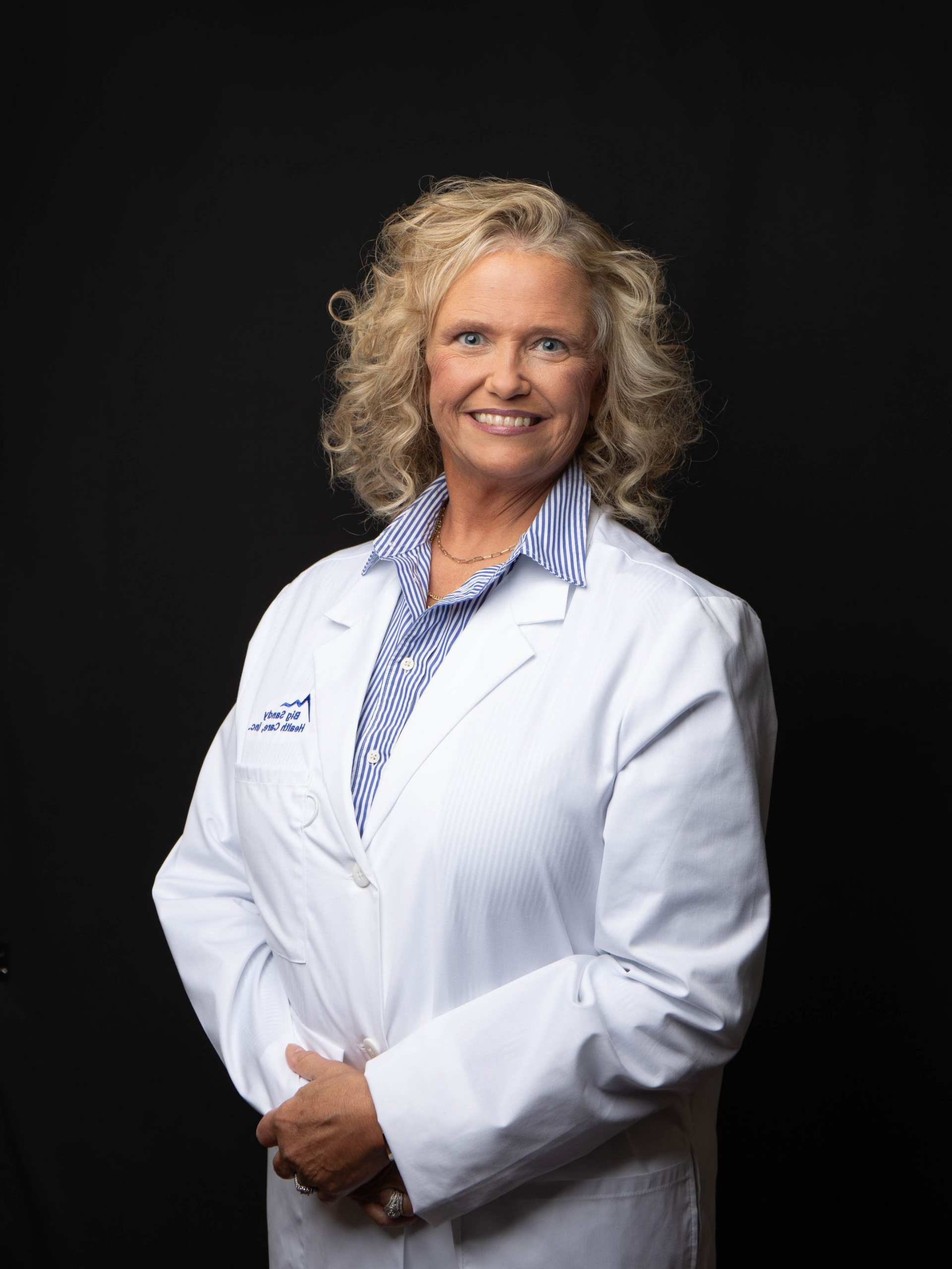 Smiling doctor in a white coat against a black background