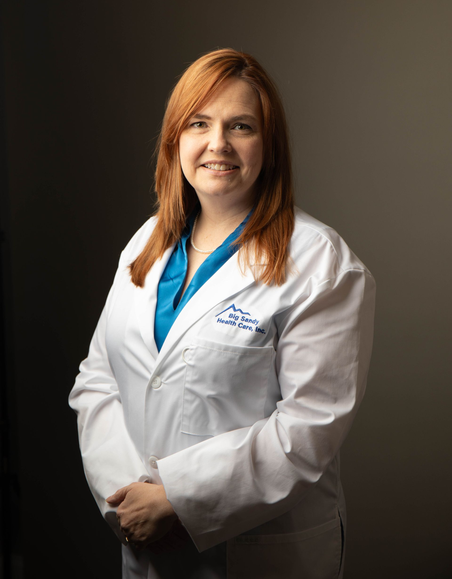 Smiling doctor in white coat with stethoscope against a dark background