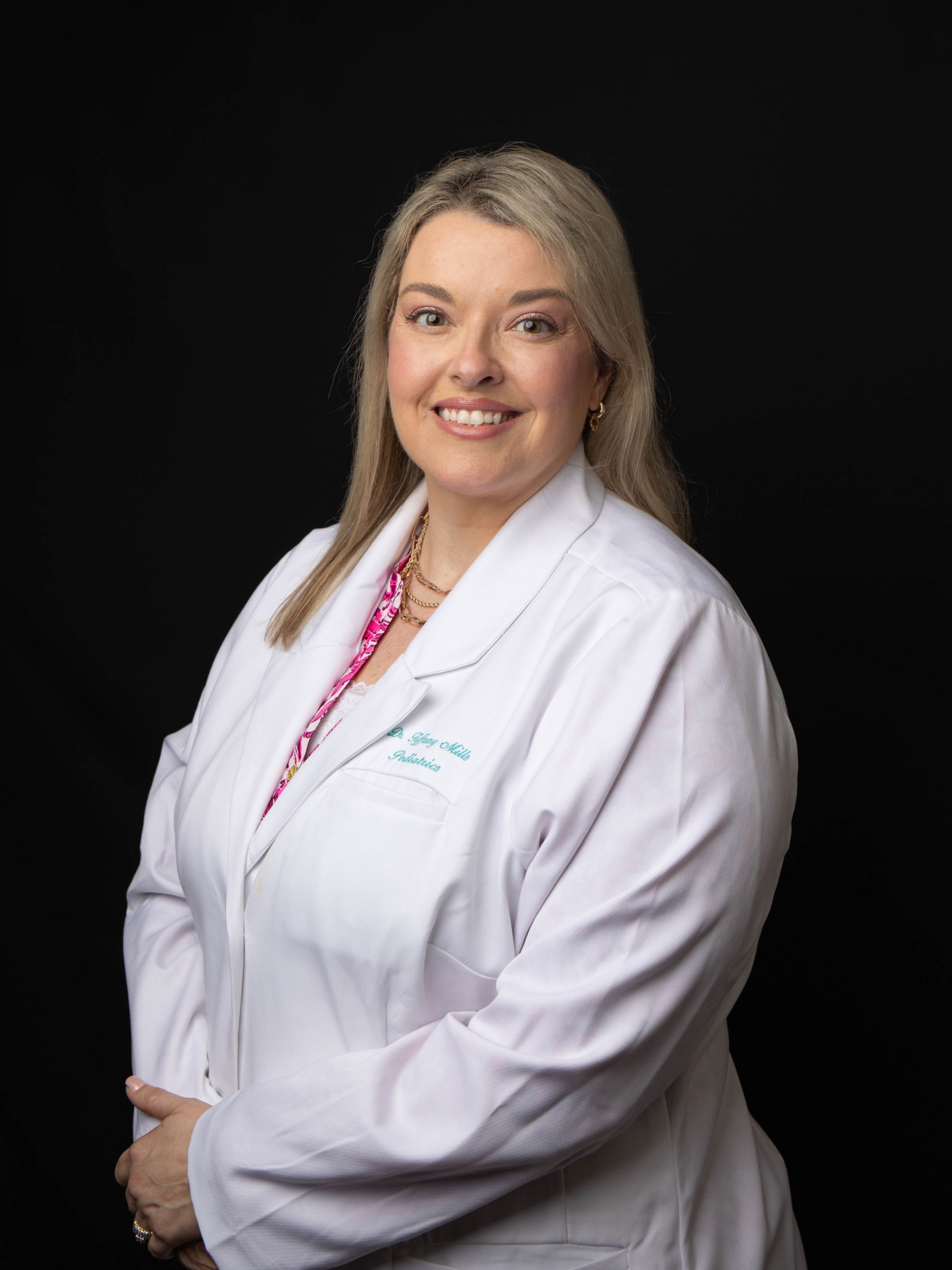 Portrait of a smiling doctor in a white coat with a stethoscope against a dark backdrop