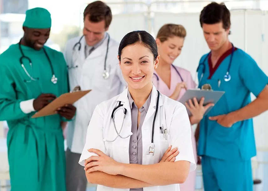 Medical team standing together in a bright hospital hallway, led by a smiling doctor in white coat.