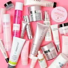 Assorted Mary Kay skincare and makeup products arranged on a pink background