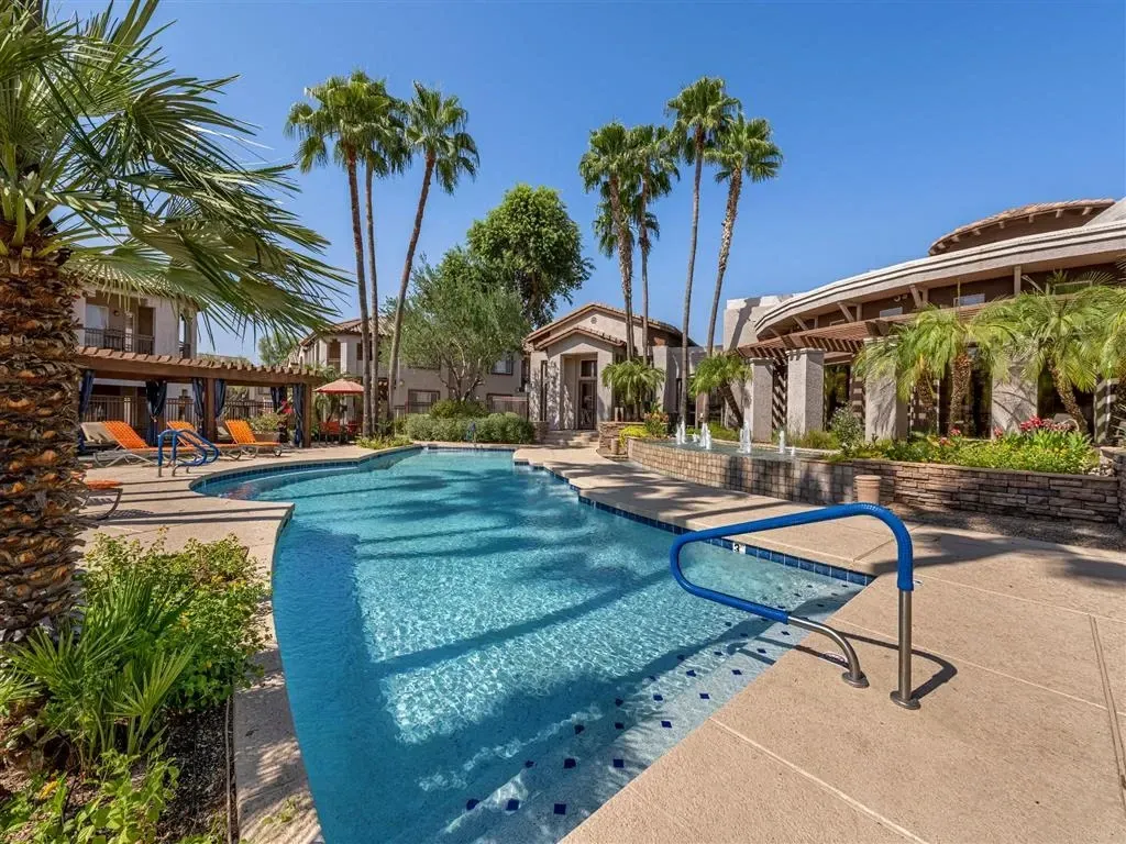Luxury apartment complex pool area with lounge chairs and palm trees