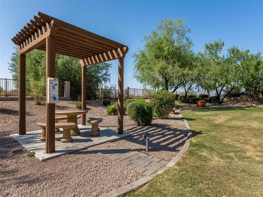 Wooden pergola with picnic table and benches in an outdoor seating area.