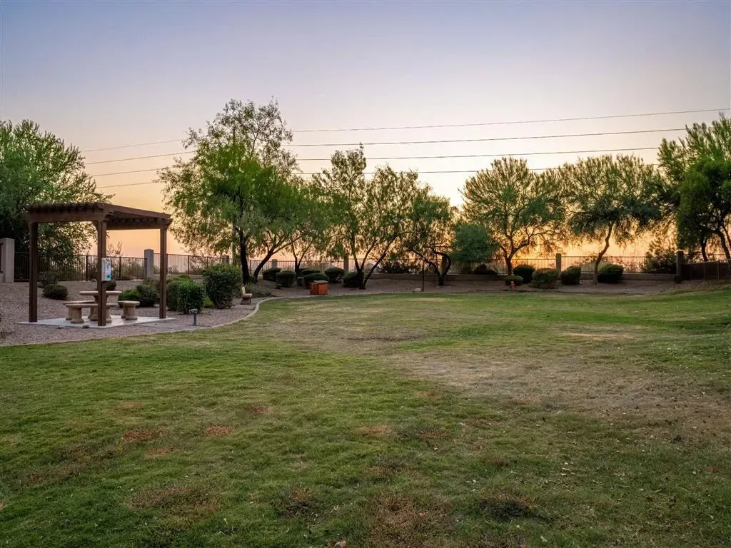 Outdoor common area with a picnic table under a pergola and a grassy lawn.