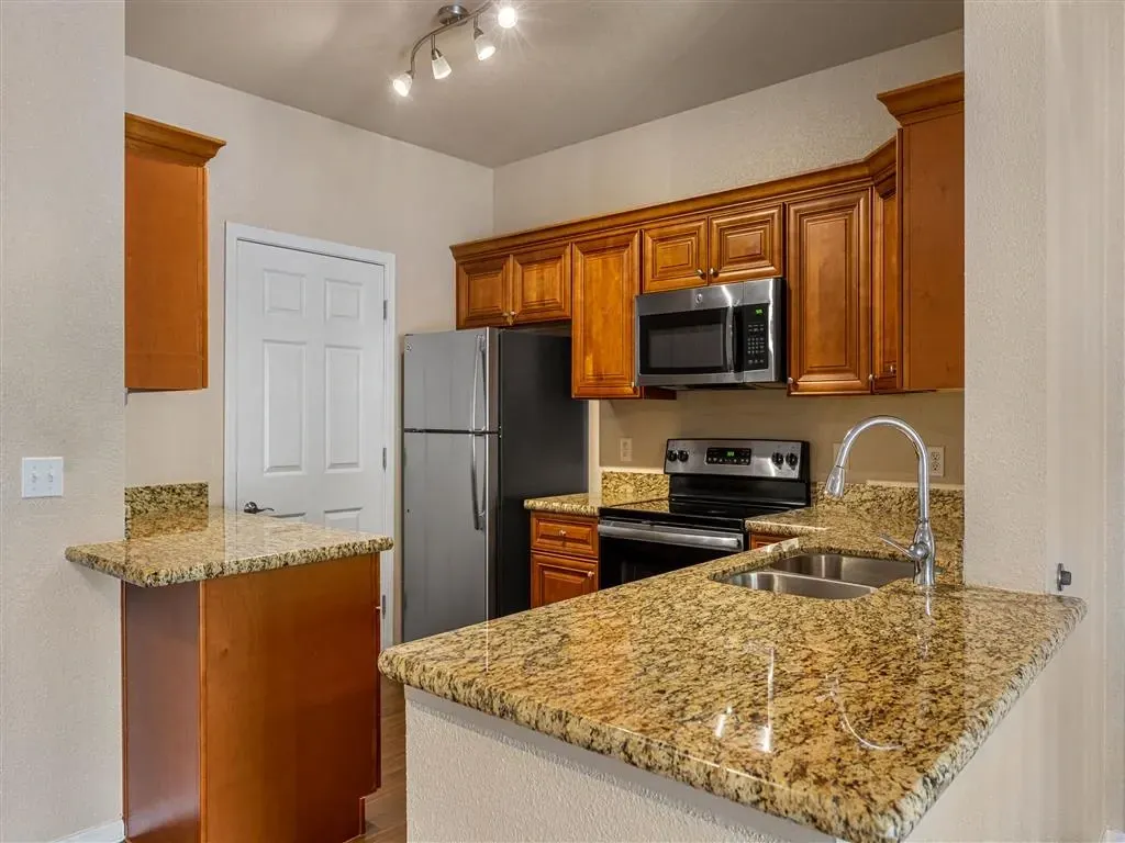 Kitchen with granite countertops, stainless steel appliances, and wooden cabinets.
