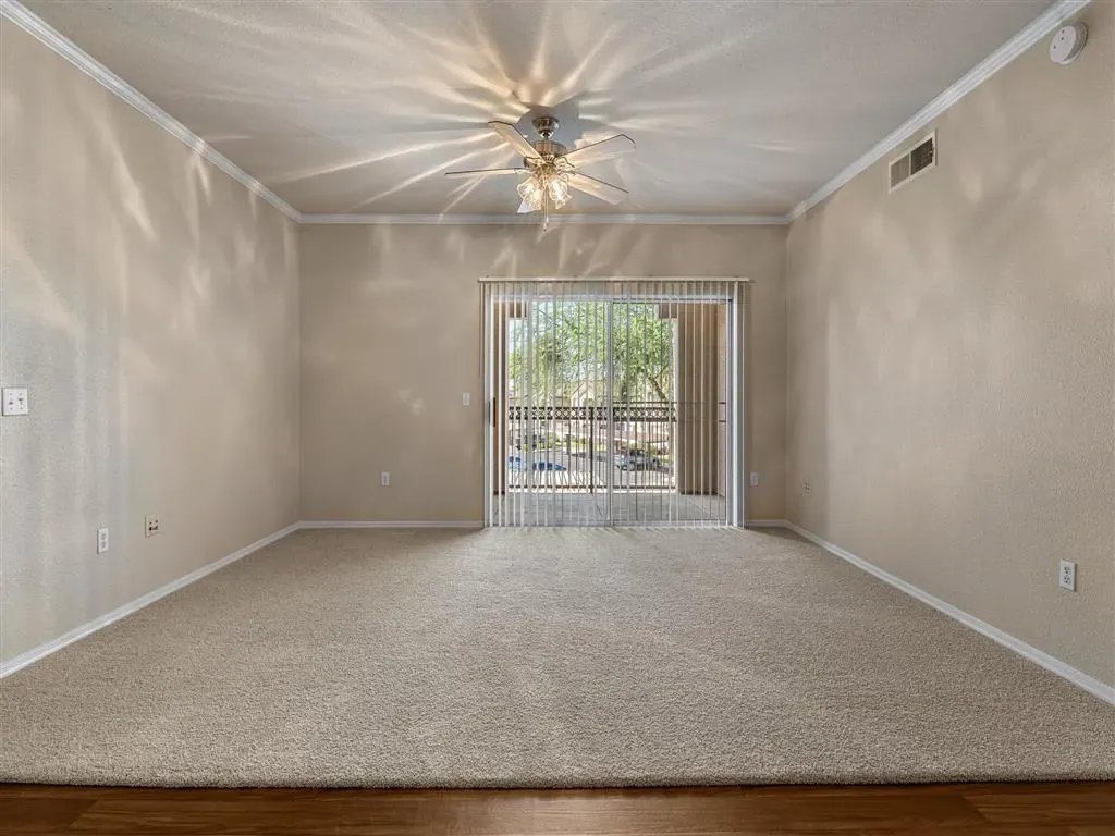 Living room with carpet, ceiling fan, and sliding glass door to balcony.