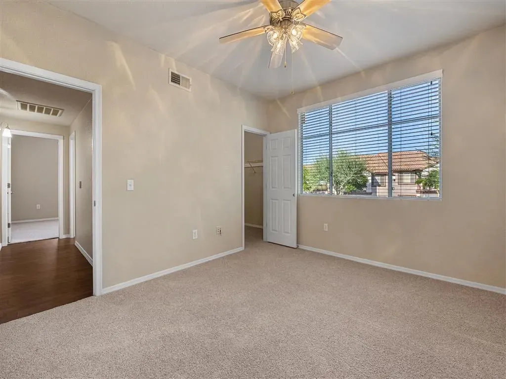 View of a bedroom with a ceiling fan and a large window.